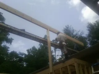 Carpenter setting a ridge beam over a new addition frame — Ice Dam Removal by Roofing Brothers in Lottsburg