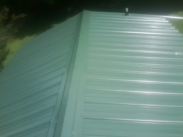 New green metal panels meeting at the ridge of a roof — Flat Roof Repair work by our crew in Lottsburg