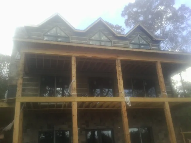 Dormers and porch framing on a large log home under construction — Roof Coating work by our crew in Lottsburg