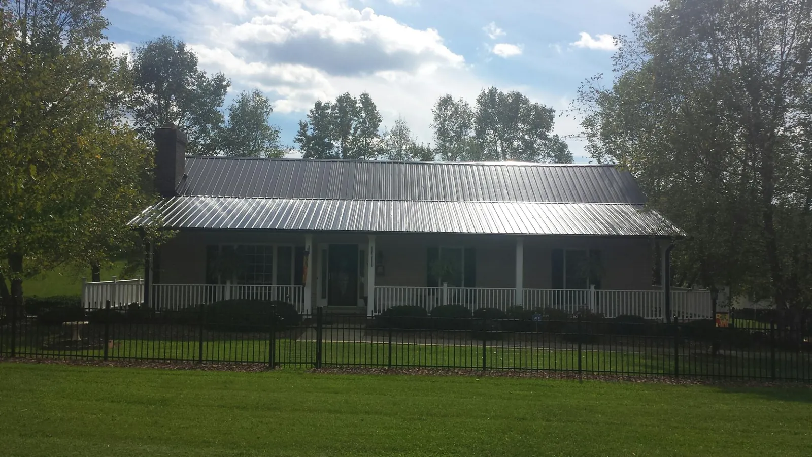 Gray metal roof on a brick ranch with a full width front porch — Gutter Guard Installation work by our crew in Lottsburg