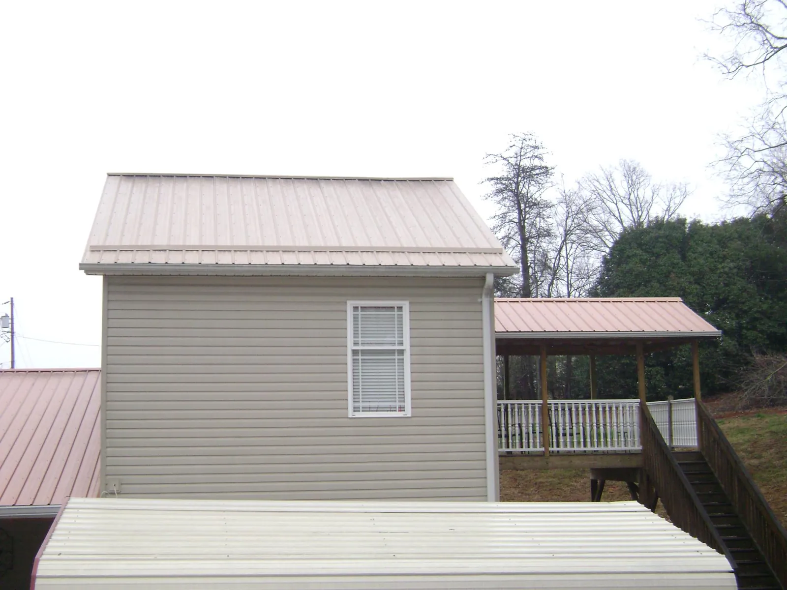 Tan metal roofs on a two story addition and attached porch, from a Roof Replacement job in Lottsburg