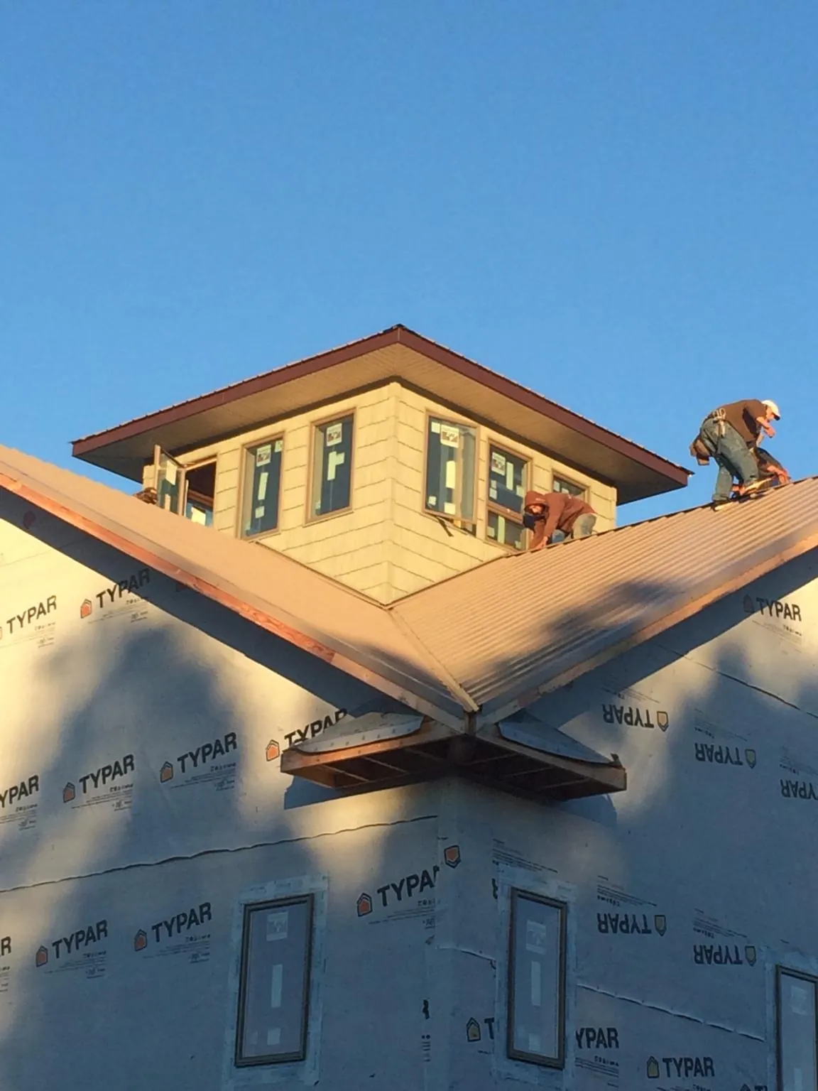 Roofers working around a rooftop cupola on a new metal roof at sunset — Roof Waterproofing in Lottsburg by Roofing Brothers